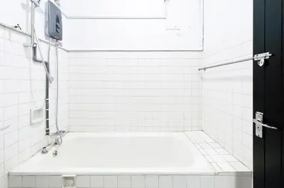 a white tiled bathroom with a bath tub in it at Homestay Taman Canning Ipoh, Perak - Smarthome in Ipoh