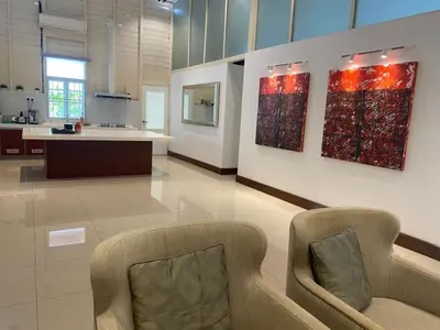 a living room with two chairs and a kitchen at Lisa Countryside Homestay in Ayer Tawar