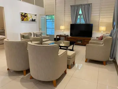 a living room with chairs and a flat screen tv at Lisa Countryside Homestay in Ayer Tawar