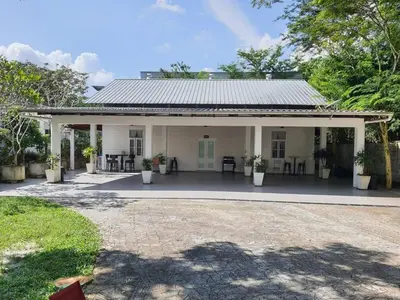 a white house with a porch with chairs and tables at Lisa Countryside Homestay in Ayer Tawar
