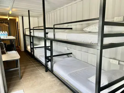 a room with three bunk beds with white sheets at The Cozytainer in Taiping