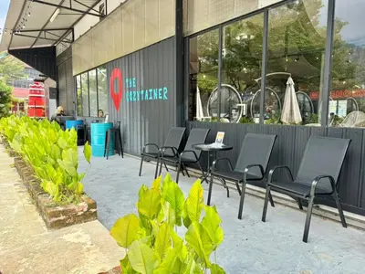 a group of chairs and a table in front of a building at The Cozytainer in Taiping