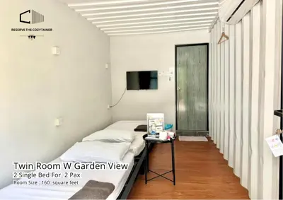 a room with a bed and a table with a tv at The Cozytainer in Taiping