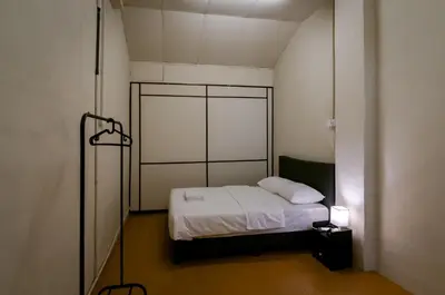 a small room with a bed with white sheets at Aayu Pantai - George Town, Penang in George Town