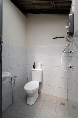a white bathroom with a toilet and a sink at Aayu Pantai - George Town, Penang in George Town