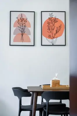 three framed prints of flowers on a wall with a table and chairs at Aayu Pantai - George Town, Penang in George Town