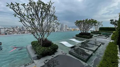 a pool of water with chairs and trees in it at Comfy 2BR Sunny Suite Sky Pool & Stunning Views in George Town