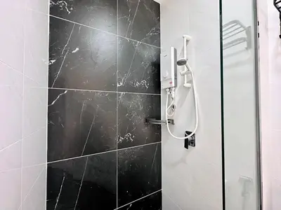 a bathroom with a shower with black tiles at Luxury 2BR SunnySuite Sky Pool Breathtaking Views in George Town
