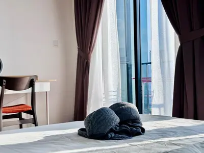 a pile of towels on a bed with a window at Luxury 2BR SunnySuite Sky Pool Breathtaking Views in George Town