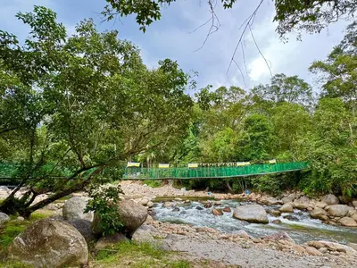 a bridge over a river with a train crossing it at Glamping in Tapah