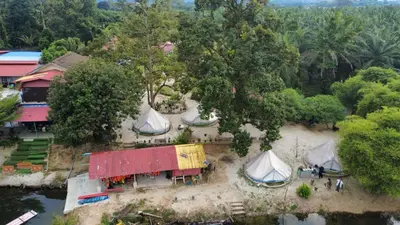 an aerial view of a house with tents next to a river at Tok Mat Village & Adventure Park in Kampong Kepayang