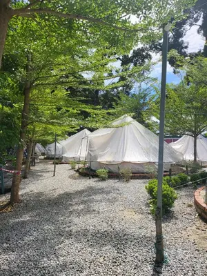 a large white tent in a park with trees at Tok Mat Village & Adventure Park in Kampong Kepayang