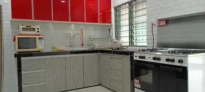 a kitchen with red cabinets and a stove and a microwave at Aloe Vera Homestay - 3 Bed Rooms Corner House in Kamunting