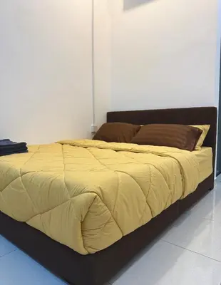 a large bed with a yellow comforter in a room at Haneya Homestay in Kampong Banggol Pasir