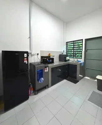 a kitchen with a black refrigerator and a counter at Haneya Homestay in Kampong Banggol Pasir