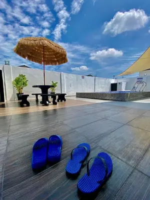 two pairs of blue flip flops and an umbrella on a patio at Lapang Tuju Private Pool Homestay in Sungai Petani