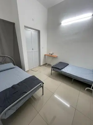 a bedroom with two beds and a table in it at Gaya's Homestay Sri Klebang in Ipoh