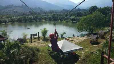 a person on a zip line over a river at Belibis Yard in Kampar