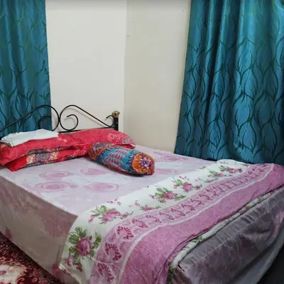 a bedroom with a bed with a pink and purple blanket at Inap Desa Jalan Baru in Kampong Sedim Number Two