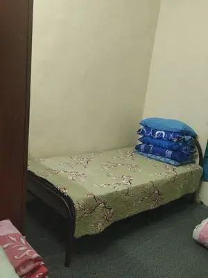 a small bed with blue pillows on top of it at Inap Desa Jalan Baru in Kampong Sedim Number Two
