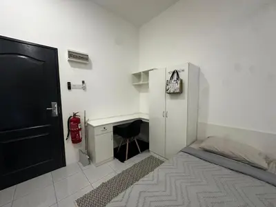a bedroom with a bed and a desk with a fire extinguisher at comfy soho in Seri Iskandar