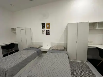 a room with two beds and a desk and cabinets at comfy soho in Seri Iskandar
