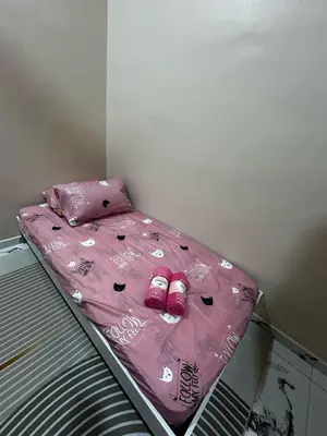 a bed with a pink comforter and shoes on it at Ariana Homestay in Sekincan