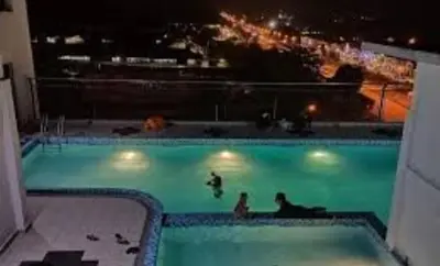 a swimming pool with people in the water at night at DikYaa Studio Apartment Pool And Netflix in Gua Musang