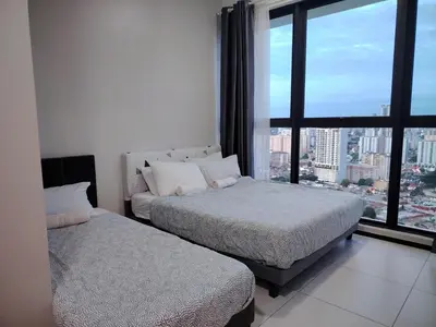 two beds in a room with a large window at The society Apartment George town 3br 10 pax in George Town