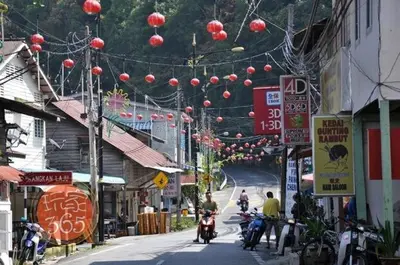 a street with people riding motorcycles down a street with signs at \u90a6\u54af\u5c9b\u6f2b\u753b\u6c11\u5bbf in Pangkor