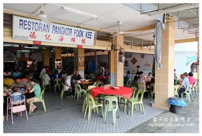 a restaurant with people sitting around tables and chairs at \u90a6\u54af\u5c9b\u6f2b\u753b\u6c11\u5bbf in Pangkor