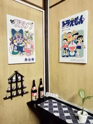 two posters on the wall of a room with a table at \u90a6\u54af\u5c9b\u6f2b\u753b\u6c11\u5bbf in Pangkor