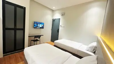 a hotel room with two beds and a desk at Legend Inn Sungai Petani in Sungai Petani