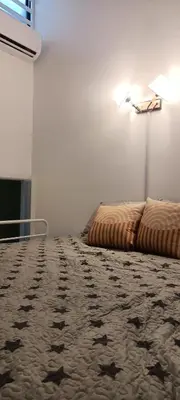 a bedroom with two beds and a lamp on the wall at HEE & PENNIE House in Ipoh