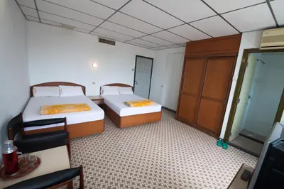 a room with two beds and a desk and a cabinet at Peking Hotel in George Town