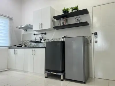 a kitchen with white cabinets and a black refrigerator at Ipoh Cozy Stay Near Town & Park in Ipoh