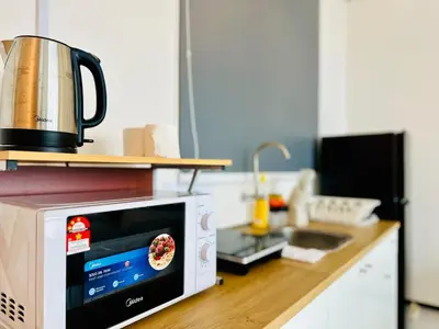 a microwave oven on a counter in a kitchen at Cozy with Sea & City Views 3BR 12PAX in Jelutong