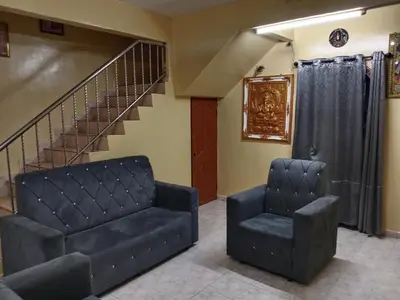 a living room with two chairs and a staircase at Krishna Villa in Simpang