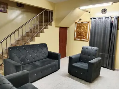 a living room with two chairs and a staircase at Krishna Villa in Simpang