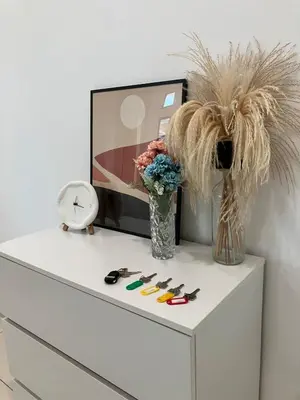a white dresser with a vase of flowers and a clock at Chicken Little 4-bedroom home with free parking! Available for Business Trip in Kampong Lima Kongsi