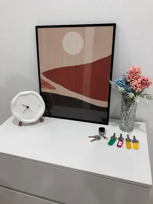 a white table with a clock and a vase of flowers at Chicken Little 4-bedroom home with free parking! Available for Business Trip in Kampong Lima Kongsi