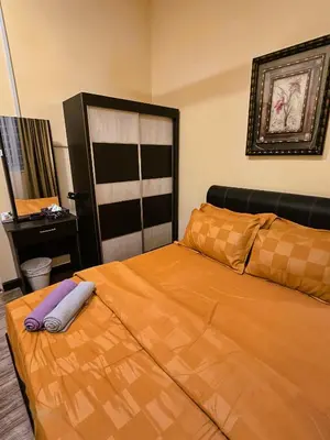 a bedroom with a bed with an orange bedspread at Homestay Desa Kati Kuala Kangsar in Kuala Kangsar