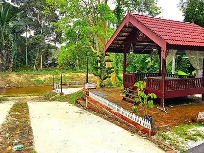 a pavilion with a red roof next to a river at Homestay Desa Kati Kuala Kangsar in Kuala Kangsar