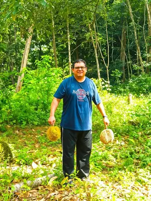a man standing in a field holding two baskets at Homestay Desa Kati Kuala Kangsar in Kuala Kangsar