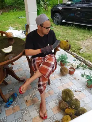 a man sitting in a chair in front of a cactus at Homestay Desa Kati Kuala Kangsar in Kuala Kangsar