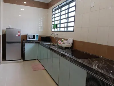 a kitchen with a counter with a sink and a refrigerator at Luxurious Noble Homestay in Sungai Petani
