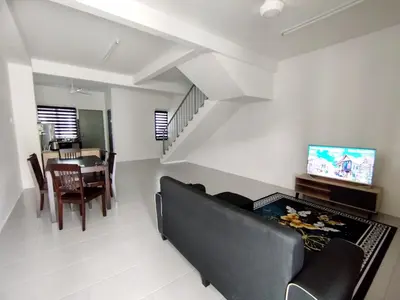 a living room with a black couch and a table at Lilly Grove Homestay in Kampong Ayer Melintas Besar