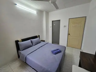 a bedroom with a bed with purple sheets and a door at Sunrise Hostel in Ipoh