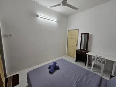 a bedroom with a bed with a purple robe on it at Sunrise Hostel in Ipoh
