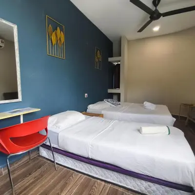 a bedroom with two beds and a red chair at Wayton Cottage in George Town